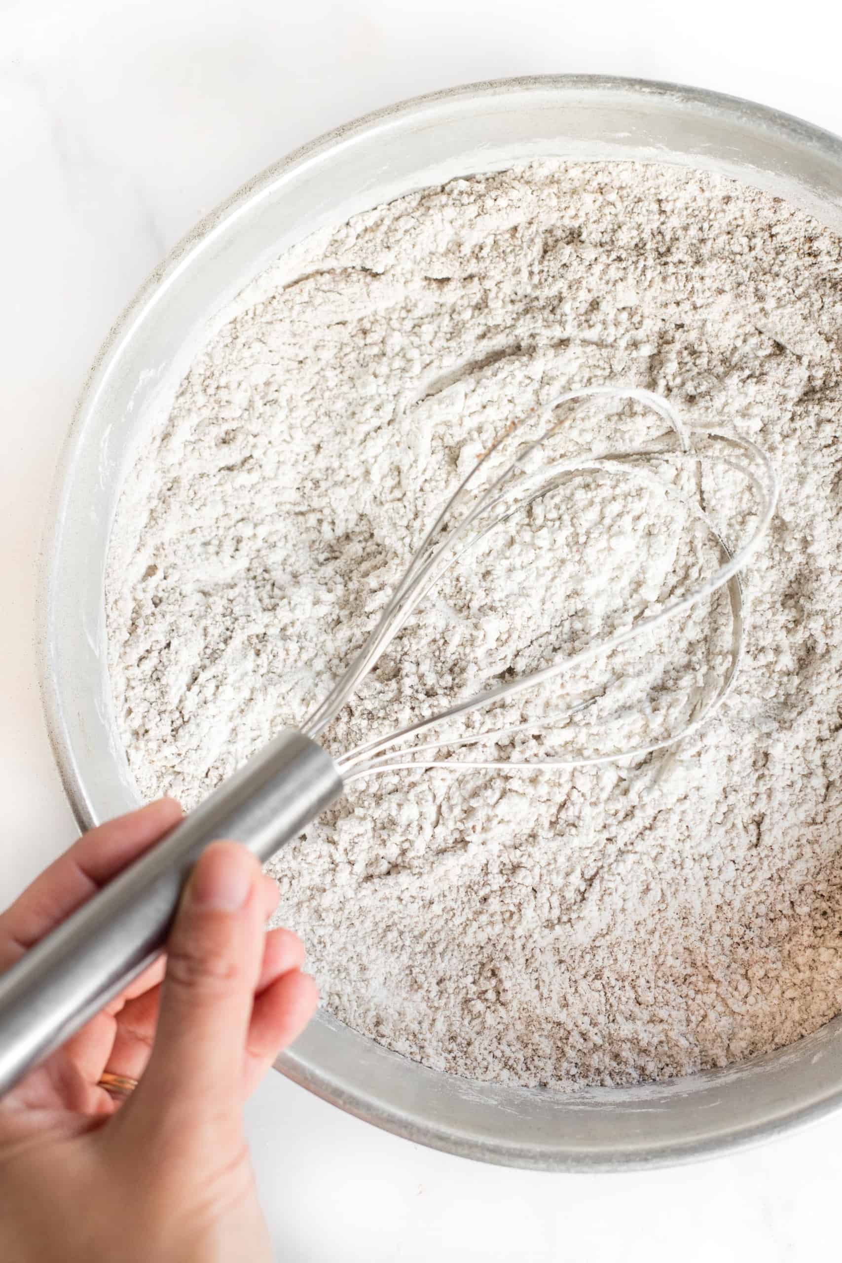 Whisking flour mixture in a large metal bowl.