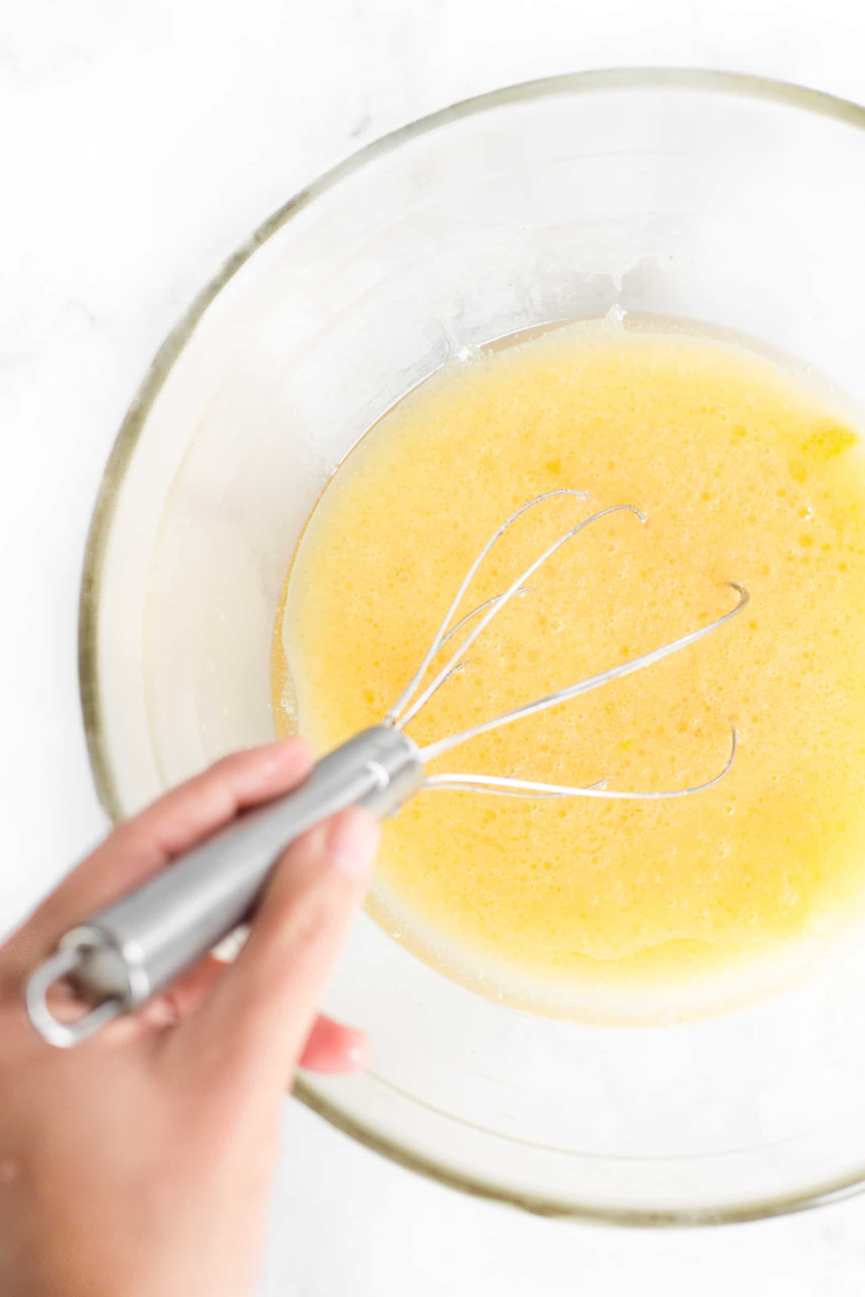 Whisking pale yellow mixture in a large glass bowl.
