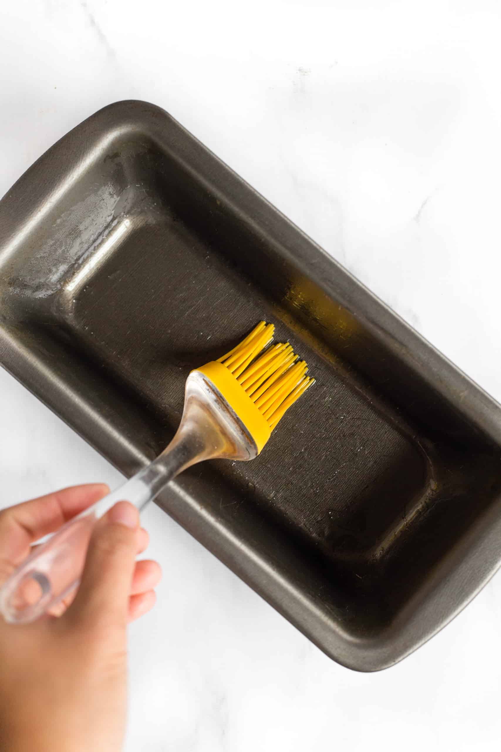 Greasing a metal loaf pan with silicon brush.