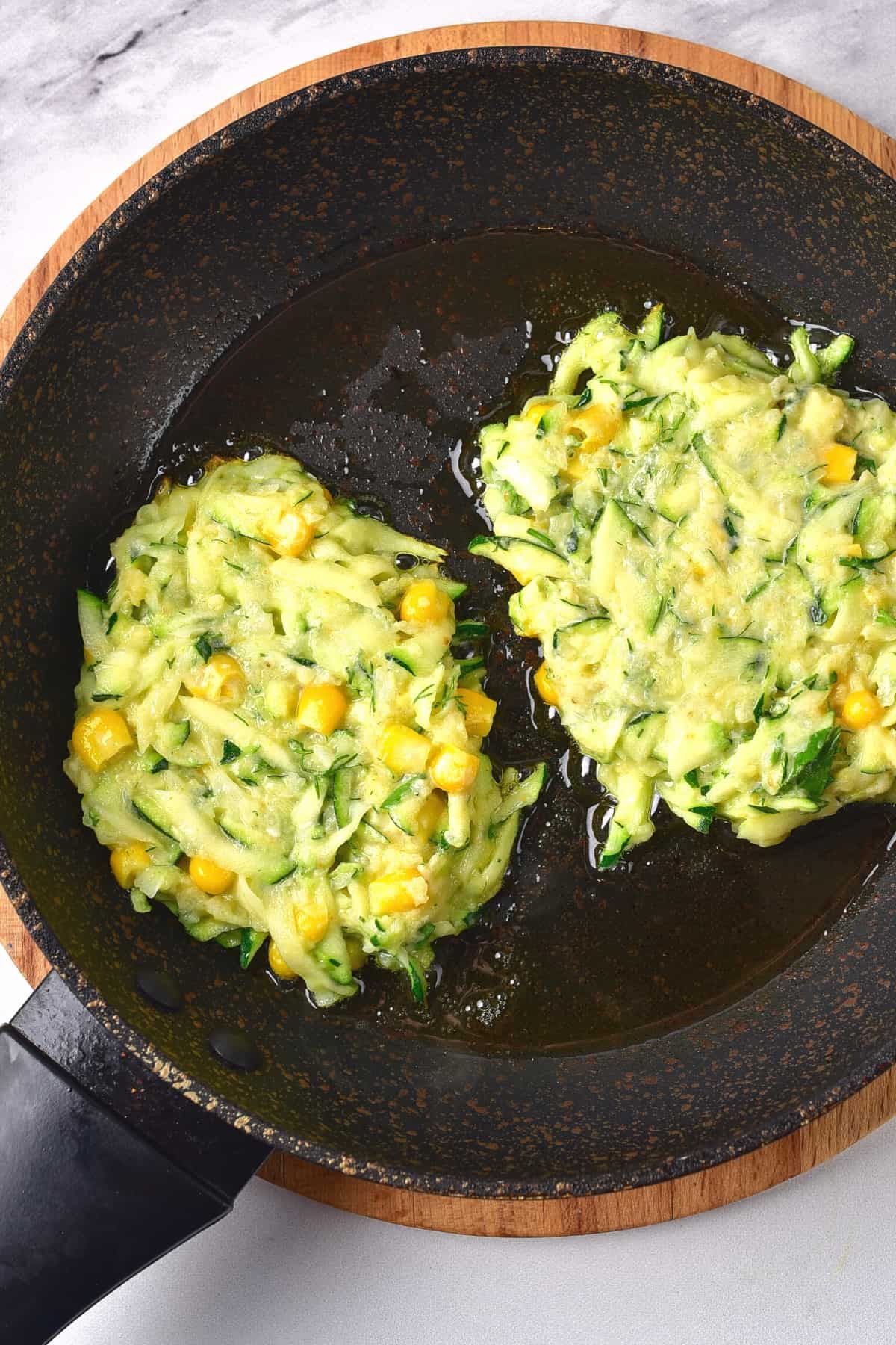 Frying zucchini fritters in a skillet.
