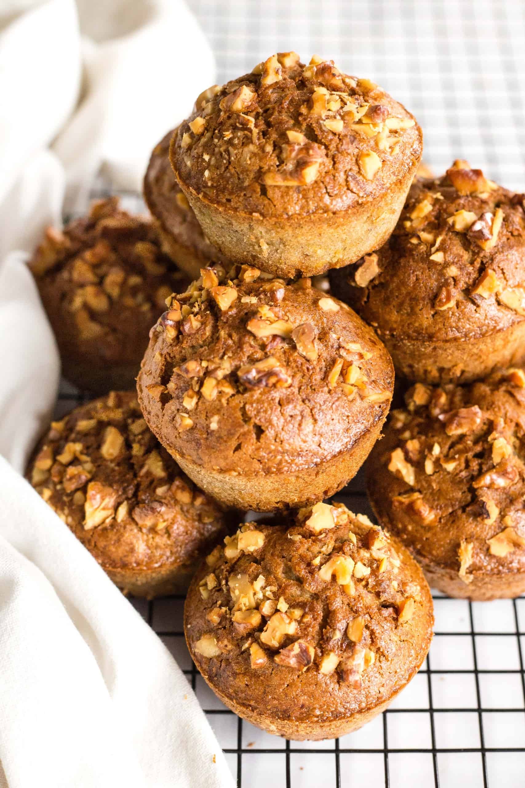 A stack of walnut-studded gluten-free muffins on wire rack.