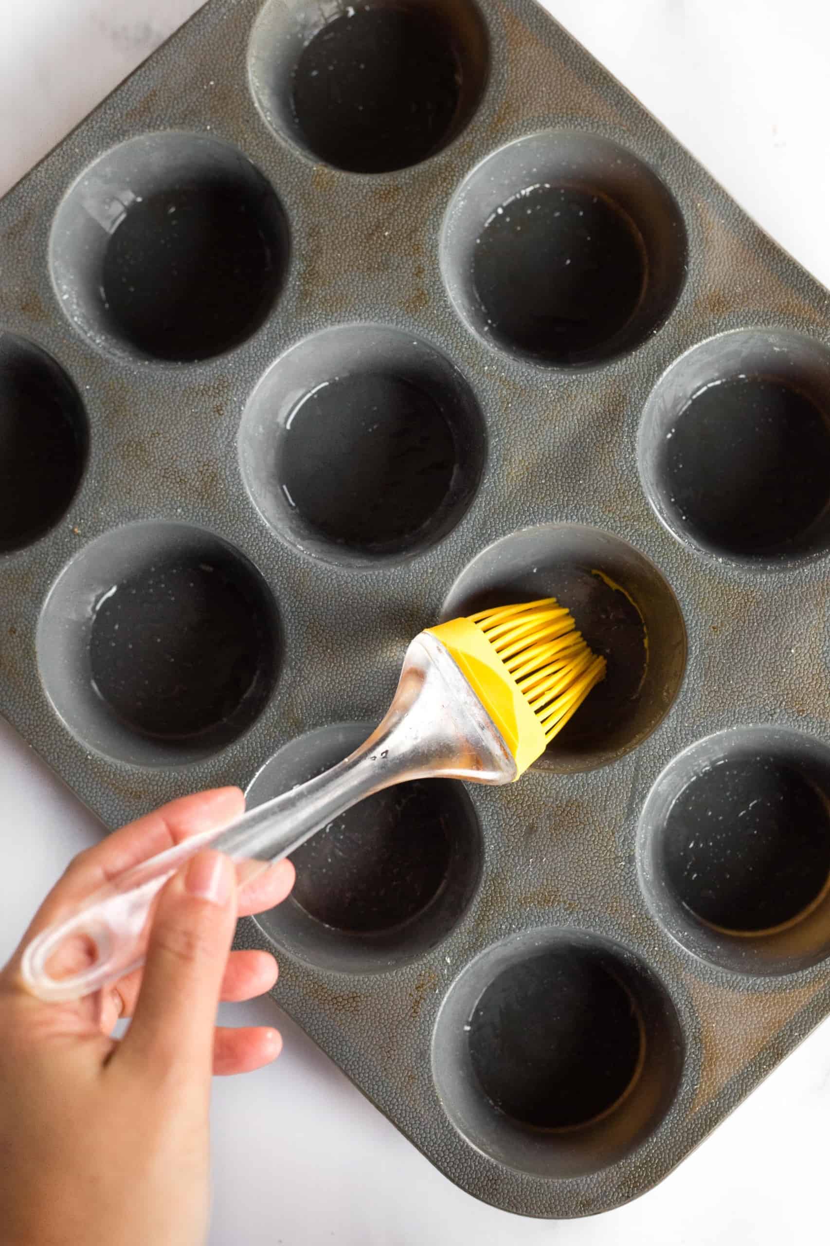 Using a yellow brush to grease a silicon muffin mold. 
