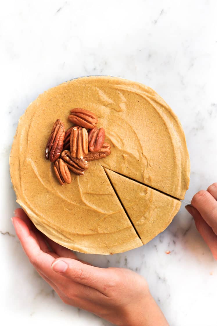 Slicing into a gluten-free pumpkin cheesecake topped with whole pecans.