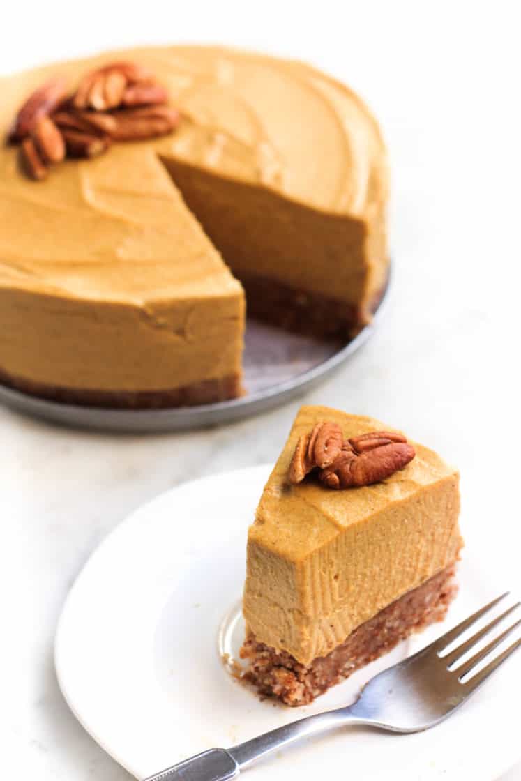 A half-eaten slice of gluten-free pumpkin cheesecake in front of the rest of the cake.