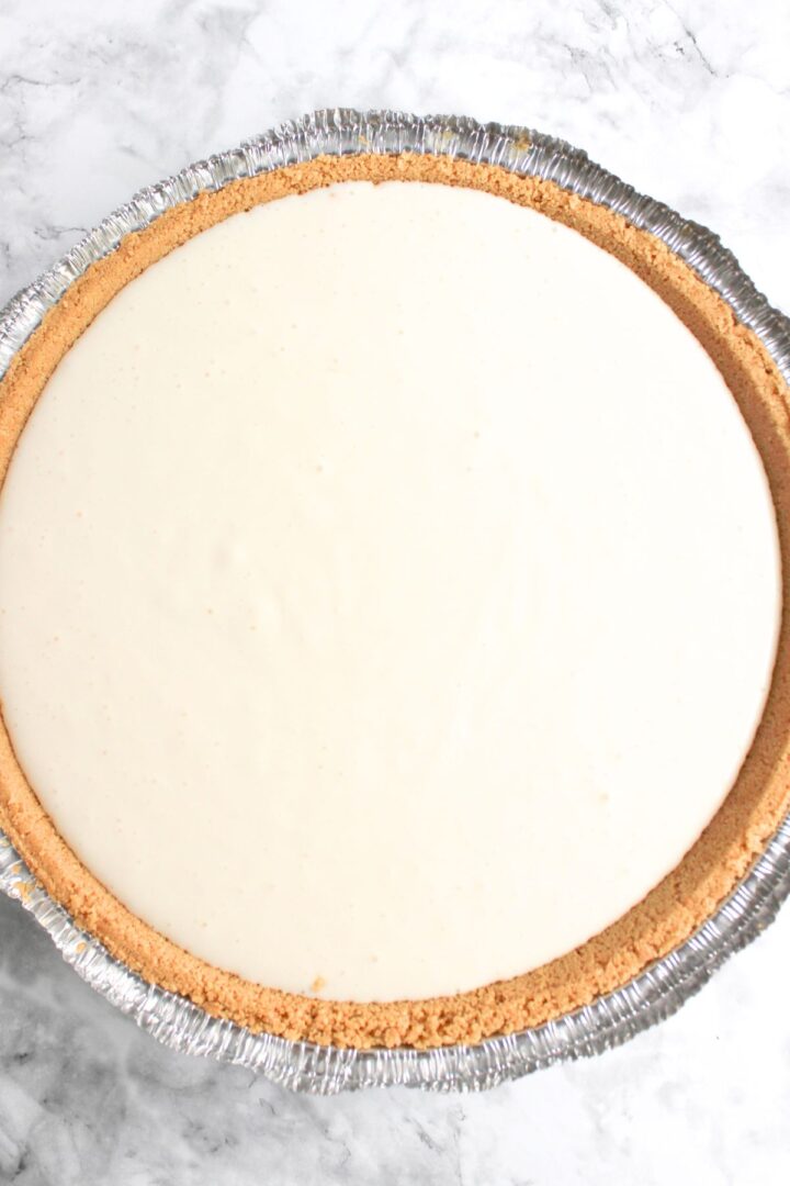 Cheesecake filling in graham cracker crust before baking