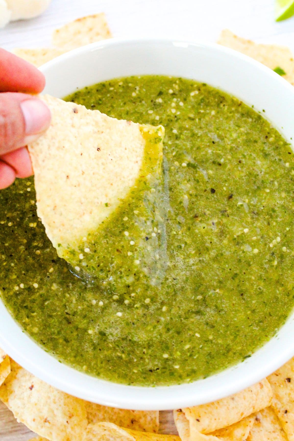 Dipping a nacho into a bowl of green tomatillo sauce