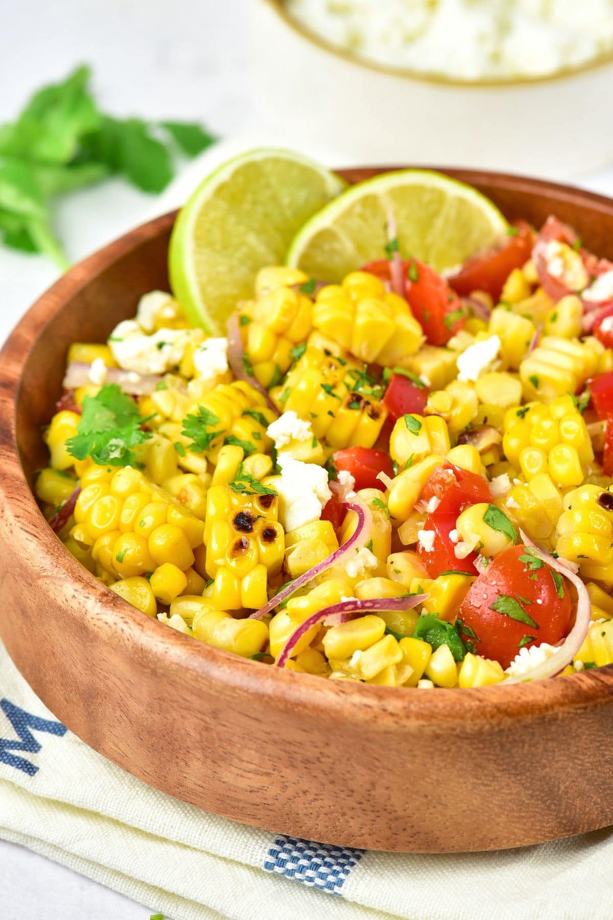 Mexican Grilled Corn Salad (Gluten-Free, Dairy-Free Option) A bowl of Mexican street corn salad with lime wedges