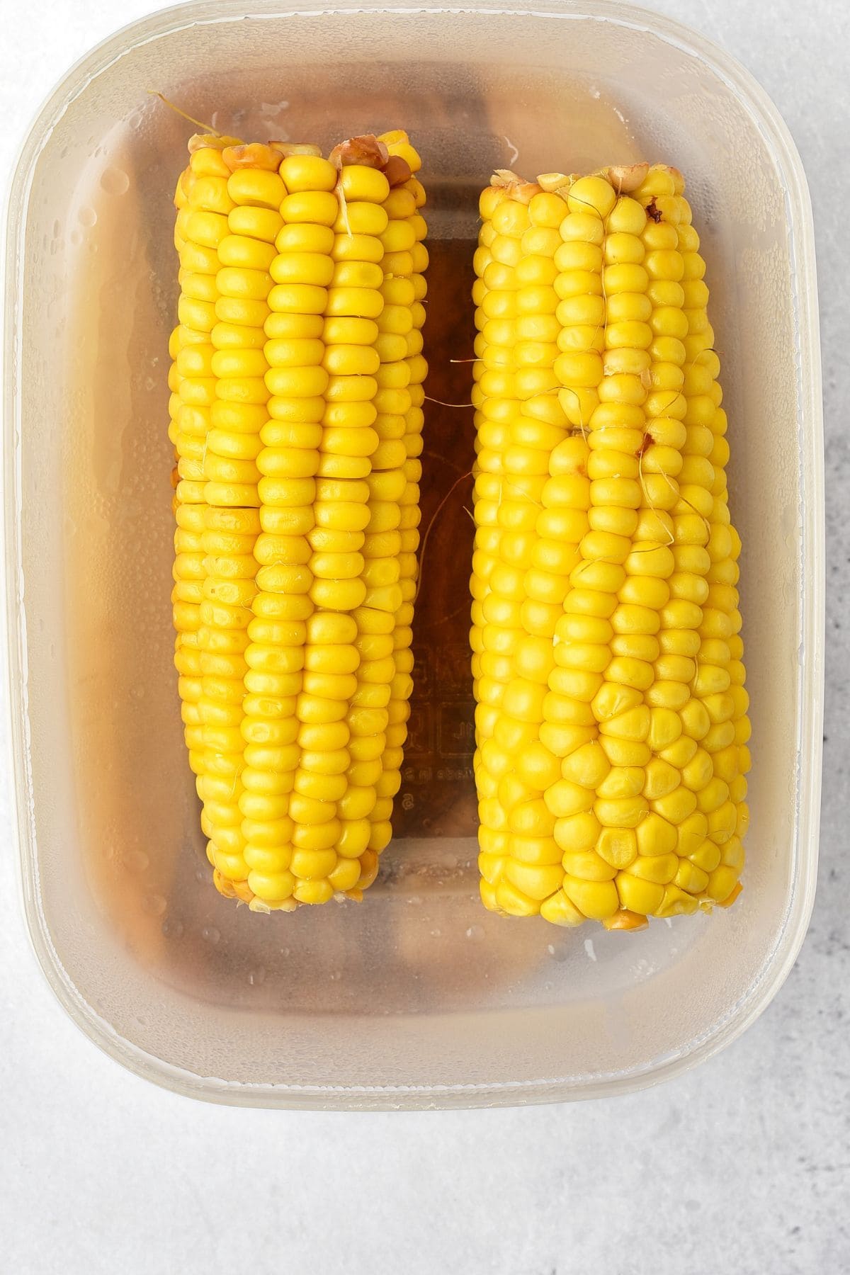 Fresh ears of corn in plastic container
