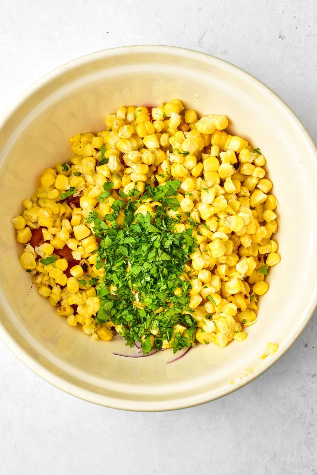 Easy Grilled Corn Salad (Gluten-Free, Dairy-Free Option) Fresh corn, tomatoes and chopped parsley in white bowl