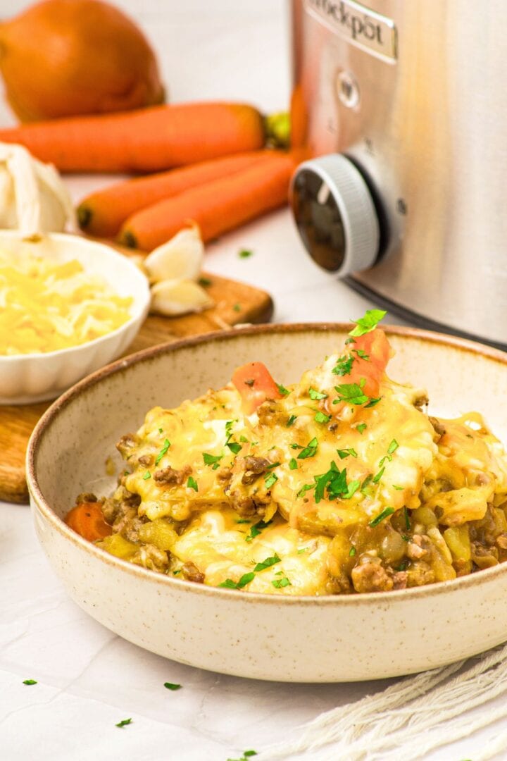 A bowl of gluten-free ground beef and potato casserole in front of a crockpot.