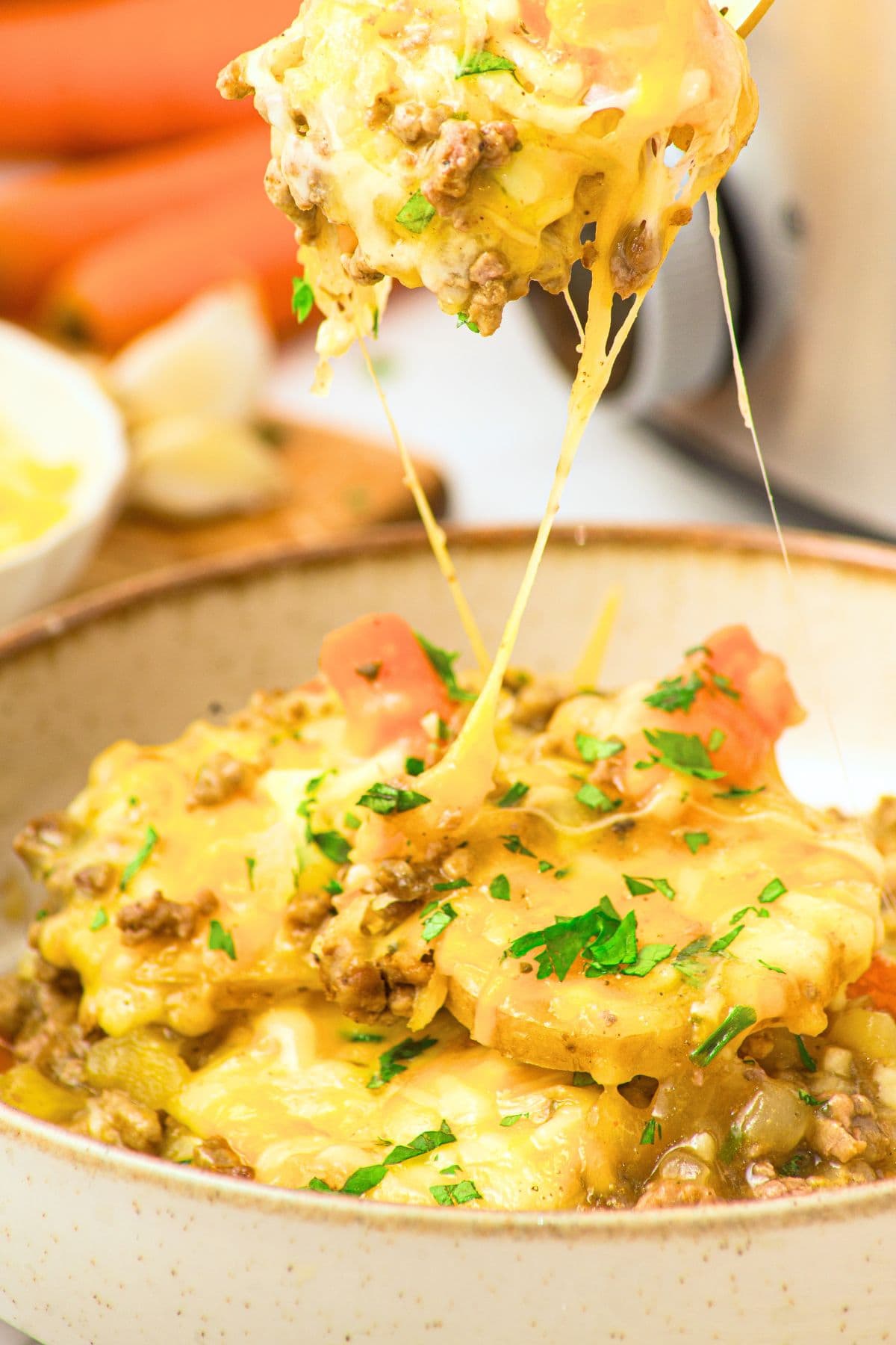 Slow Cooker Ground Beef and Potato Casserole (Gluten-Free, Dairy-Free) Holding up a spoonful of ground beef and potato casserole from a bowl.