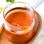 A glass container with guajillo chile sauce.