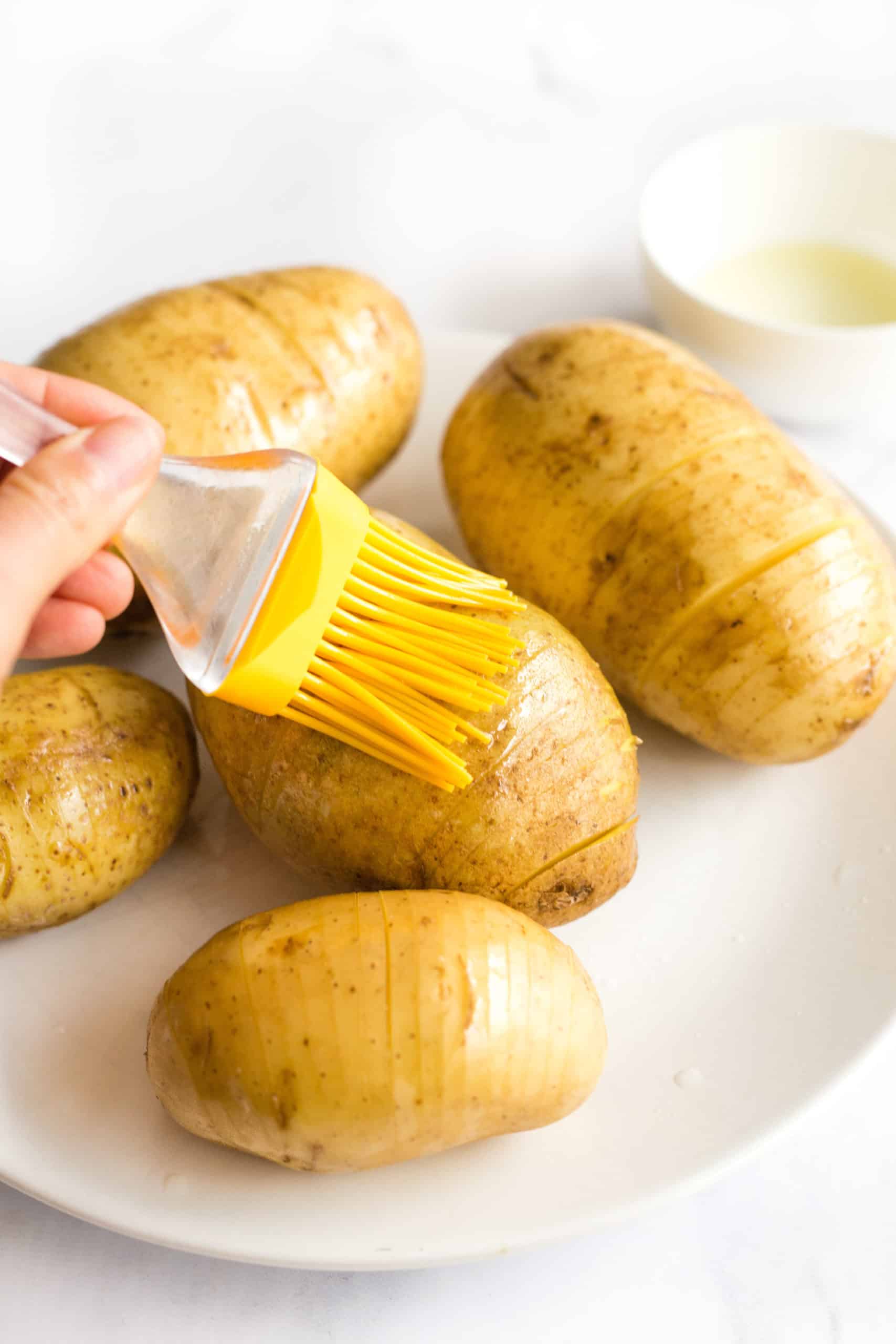Using a silicon brush to brush sliced potatoes with oil.