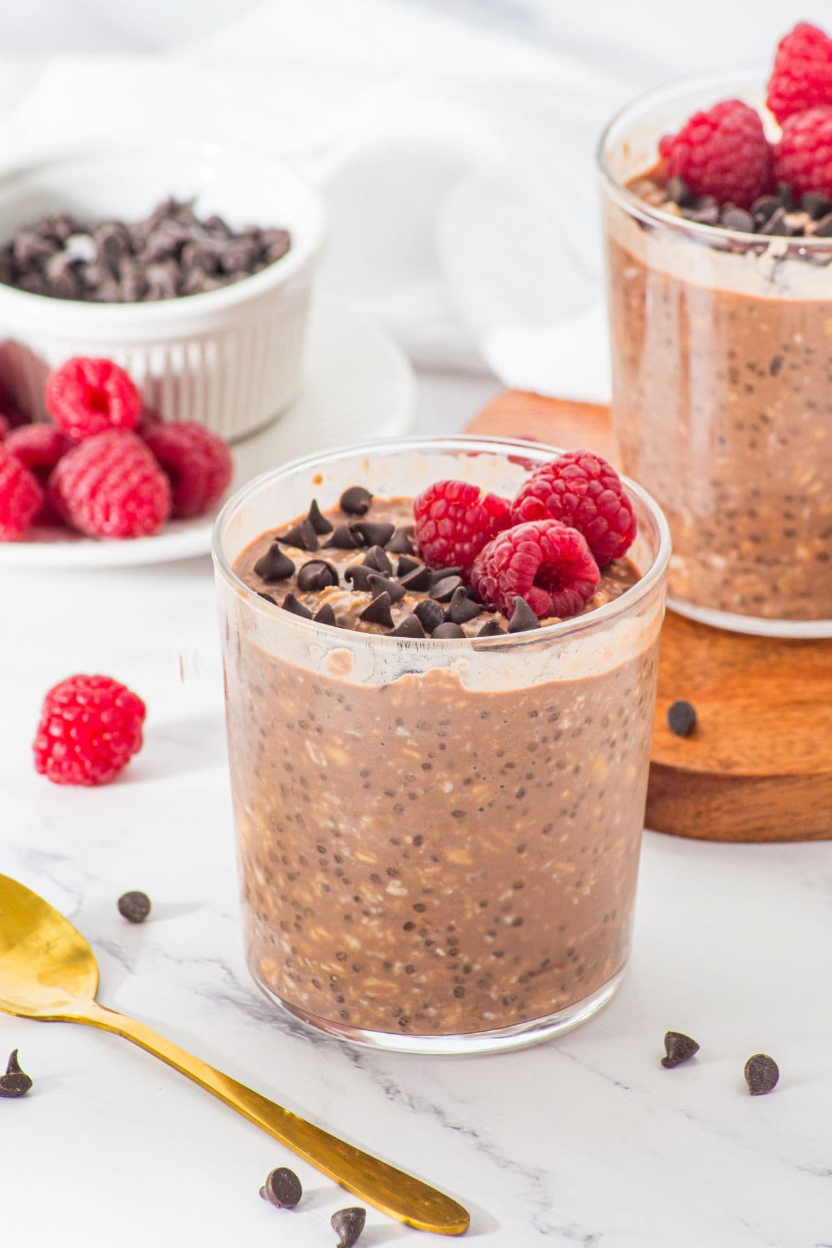 Glasses of chocolate chip overnight oats and raspberries