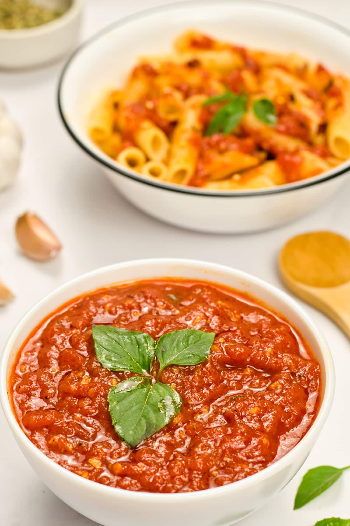 A bowl of marinara sauce topped with basil leaves.