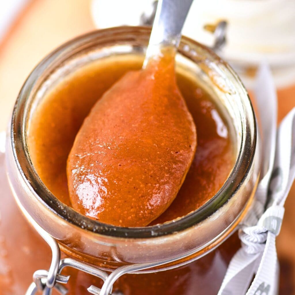 Holding up a spoonful of apple butter from a jar