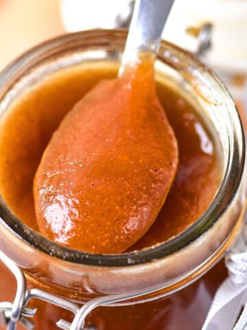 Holding up a spoonful of apple butter from a jar