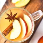 A glass of apple cider on wooden board.