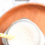 A glass of cashew milk on a wooden board.