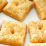Cheese crackers spread out on white board.