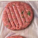 Top down view of gluten-free hamburger patties on plastic sheet.