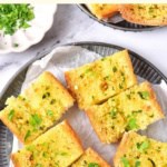 Top down view of garlic bread on parchment-lined plate.