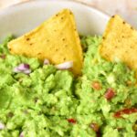 Tortilla chips in a bowl of gluten-free guacamole.