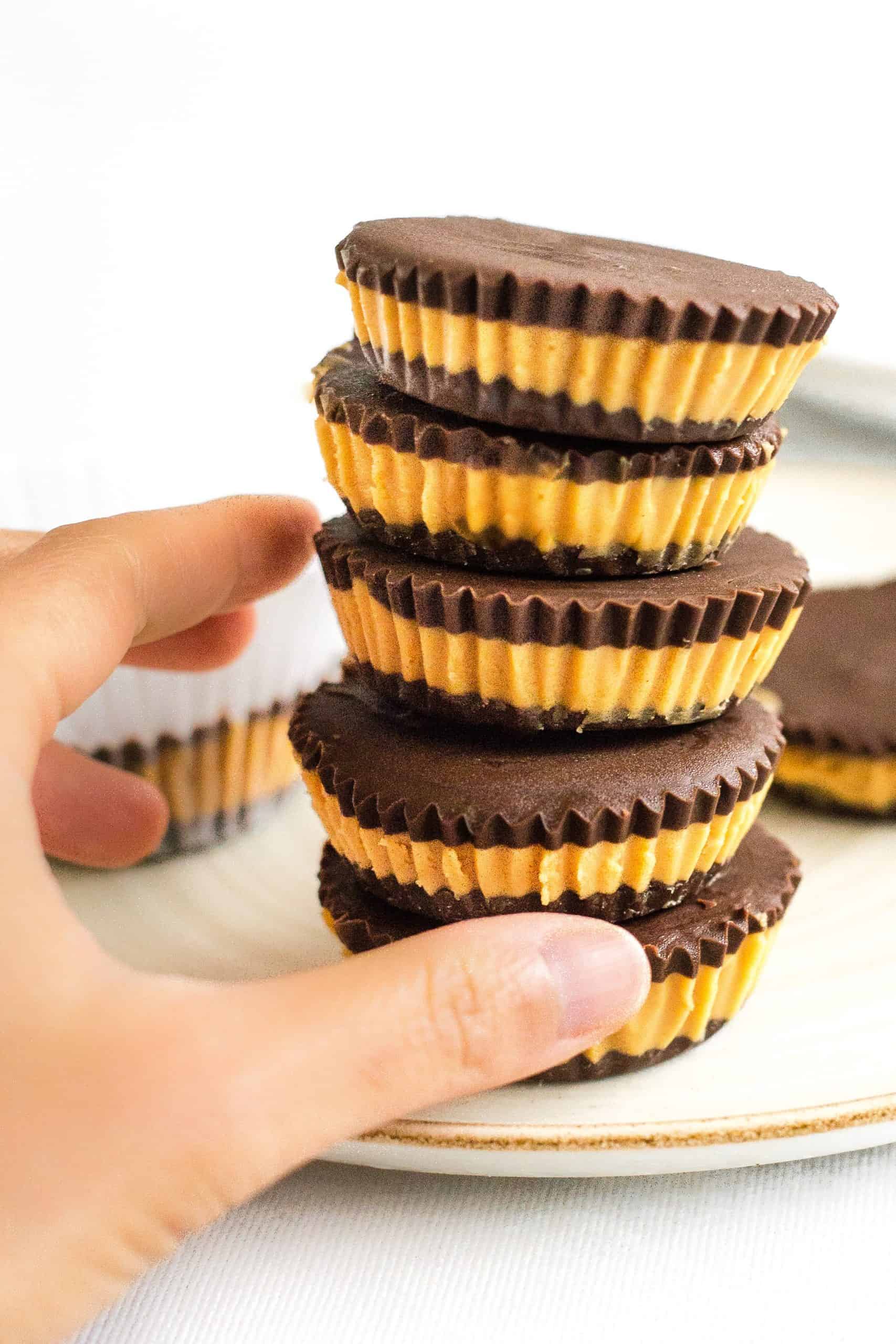 Hand reaching for a stack of healthy peanut butter cups.