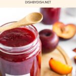 A jar of homemade plum jam on wooden board