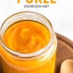 A jar of pumpkin puree on a wooden board.