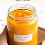 Hand holding a jar of homemade pumpkin puree