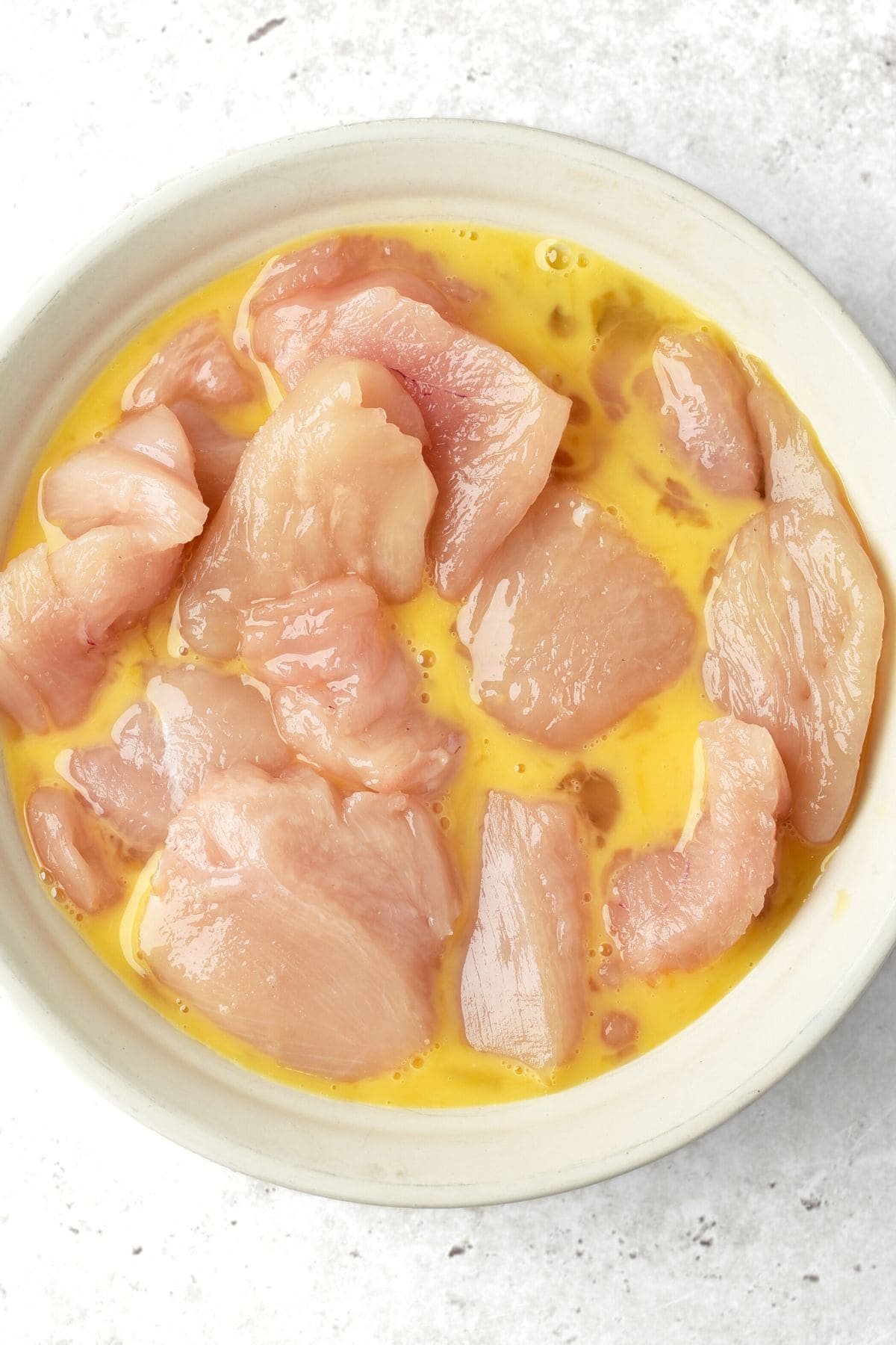 Turkey pieces in bowl of beaten egg.