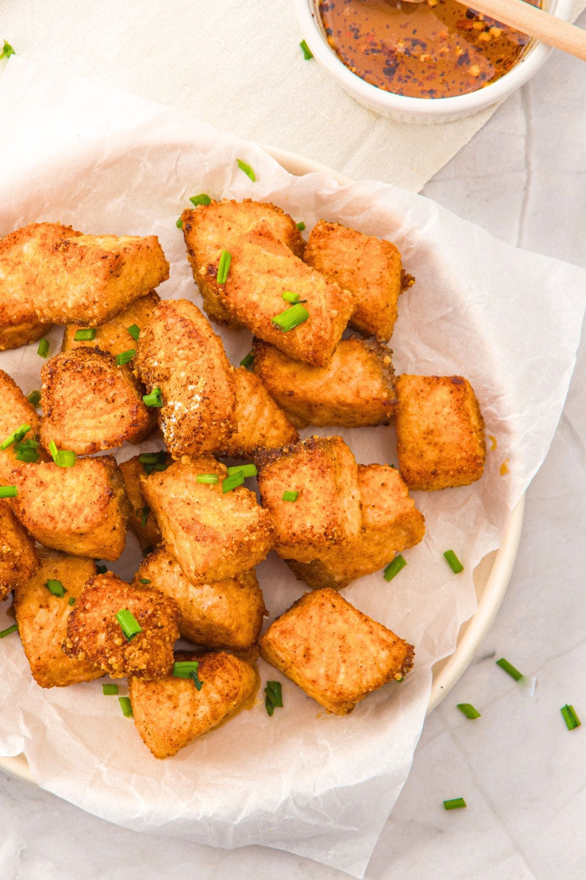 Top down view of hot honey salmon bites on parchment-lined plate