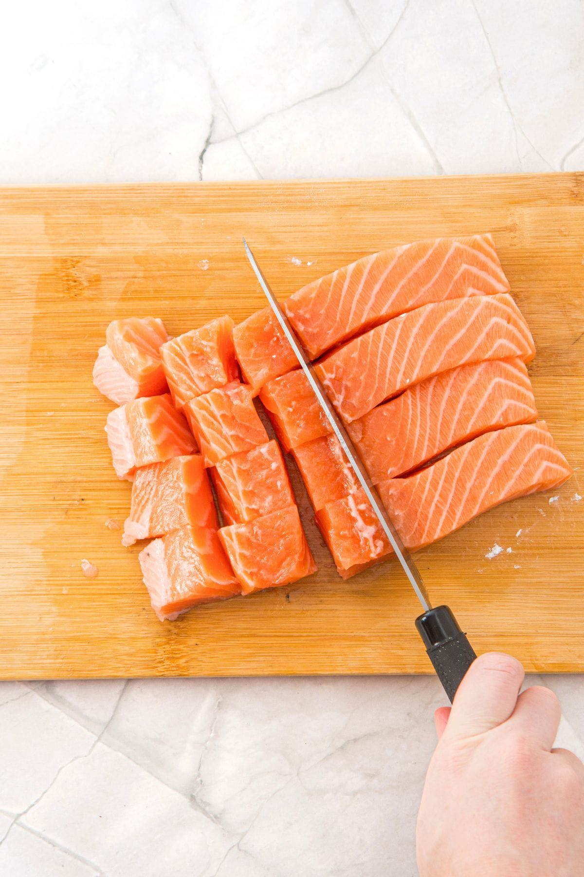 Cutting fresh salmon into cubes