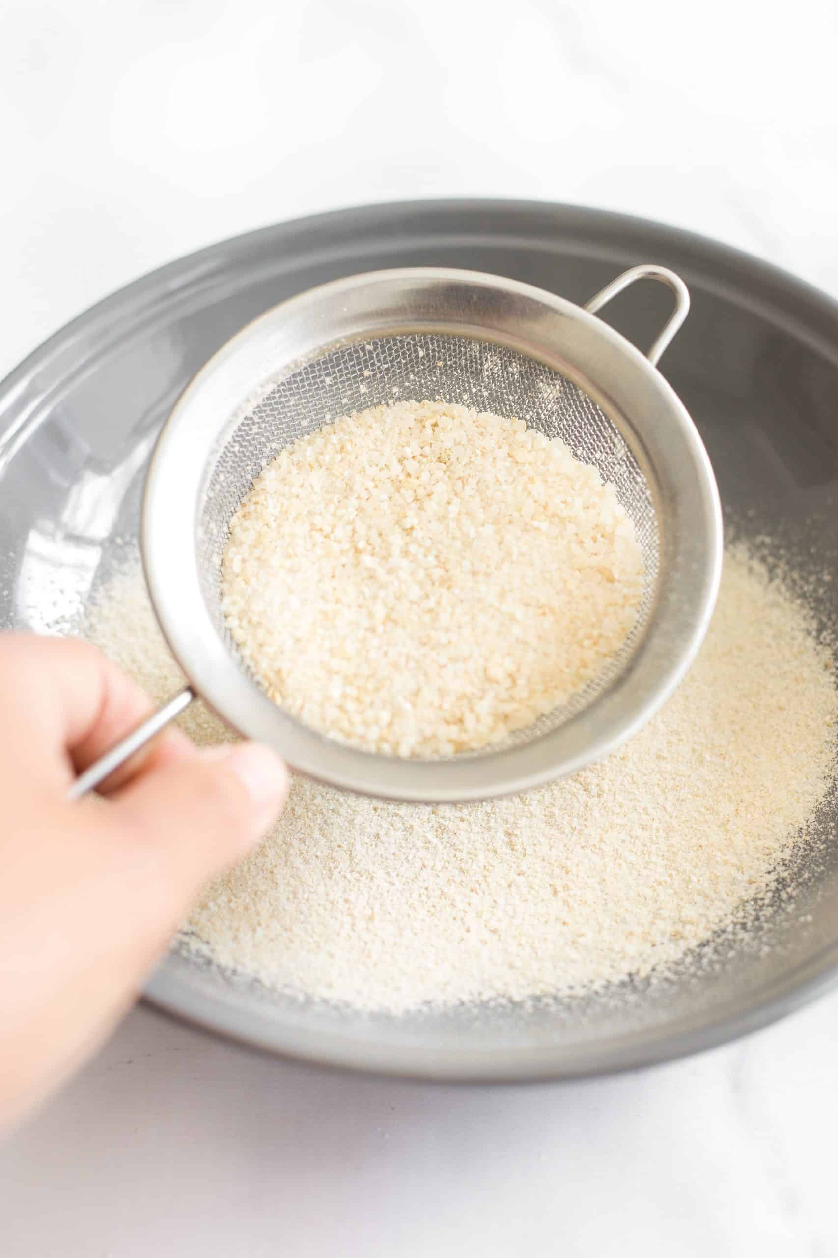 Sifting rice flour through a fine-mesh sieve.