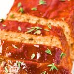 Sliced chicken meatloaf topped with fresh thyme.