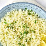 Top down view of a spoon in bowl with cilantro cauliflower rice