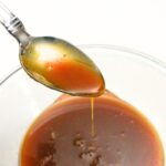 Holding up a spoonful of caramel over a bowl.