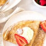 A plate of crepes topped with berries and cream.