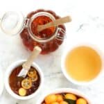 Kumquat marmalade and fresh kumquats on marble board.