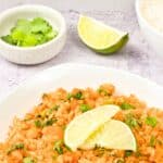 A bowl of red Mexican rice topped with lime slices.