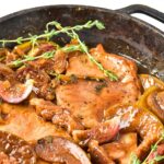 A skillet full of pork chops and caramelized apples.