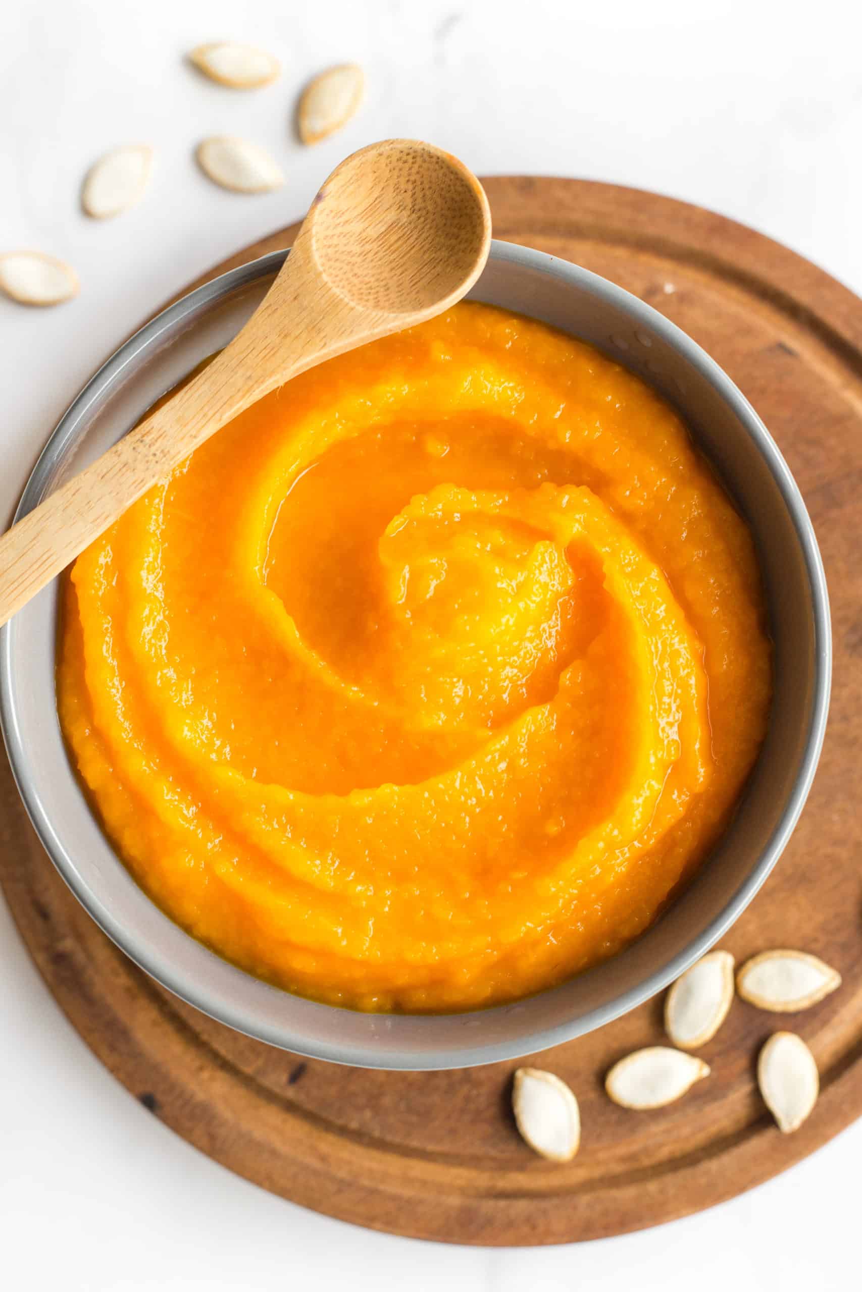 A bowl of freshly made pure pumpkin puree on a wooden board.