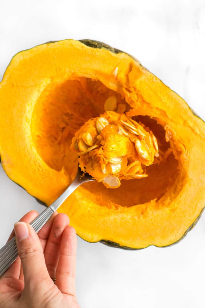 Scooping out pumpkin seeds from a cut pumpkin.