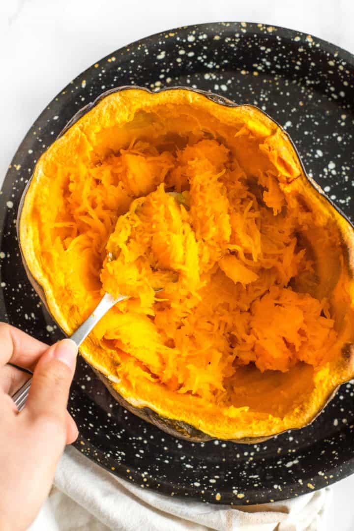 Scooping out roasted pumpkin flesh from the skin.