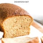 A sliced loaf of bread on parchment-lined wooden board.