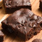 Up close view of brownies on wooden board.