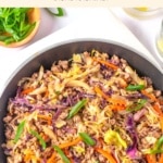 A skillet of sautéed meat and veggies on kitchen towel.