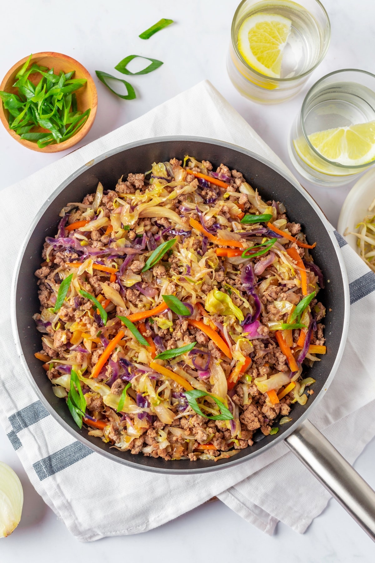 A skillet with egg roll stir fry on a kitchen towel.
