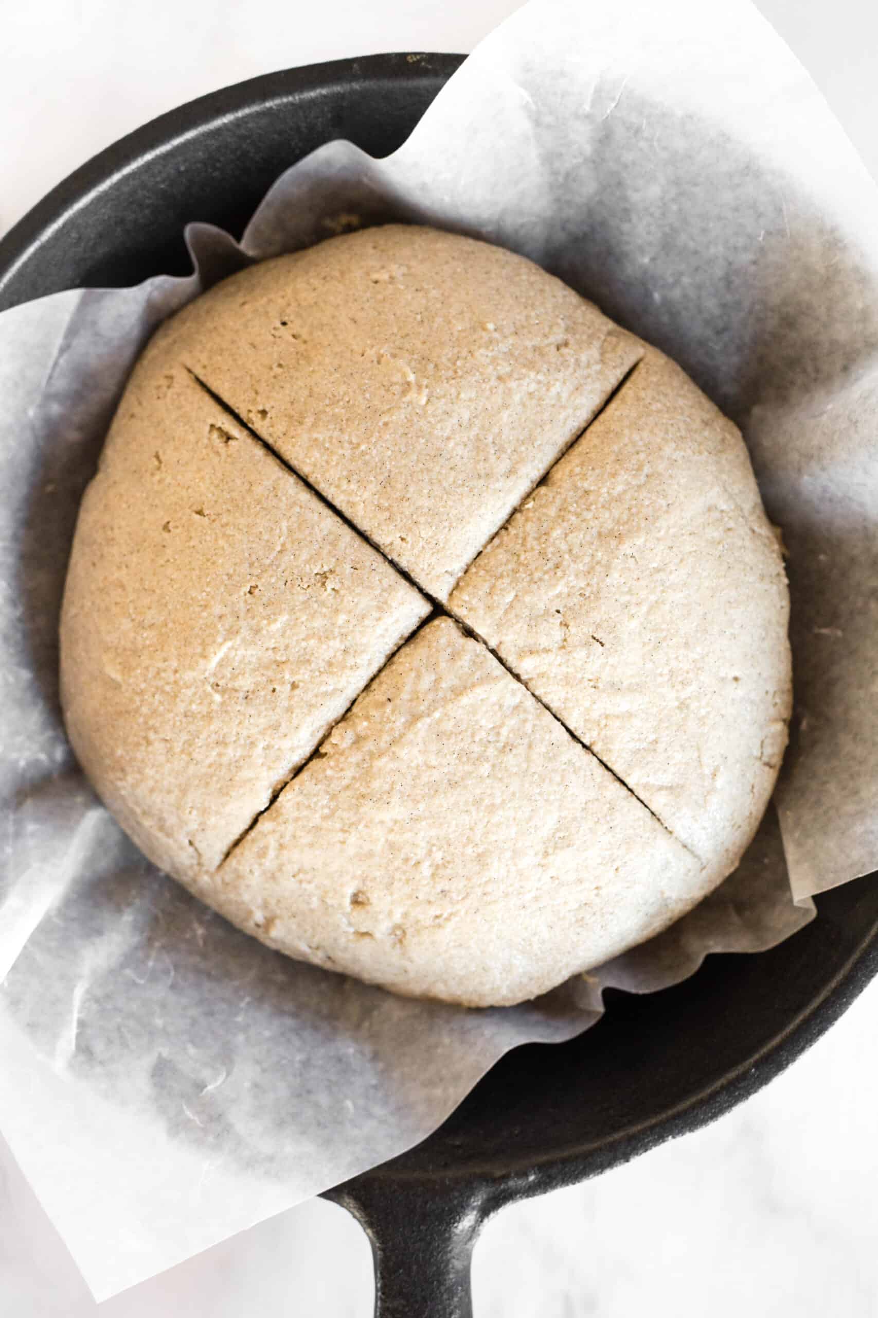 Bread dough with a cross cut on top of the dough.